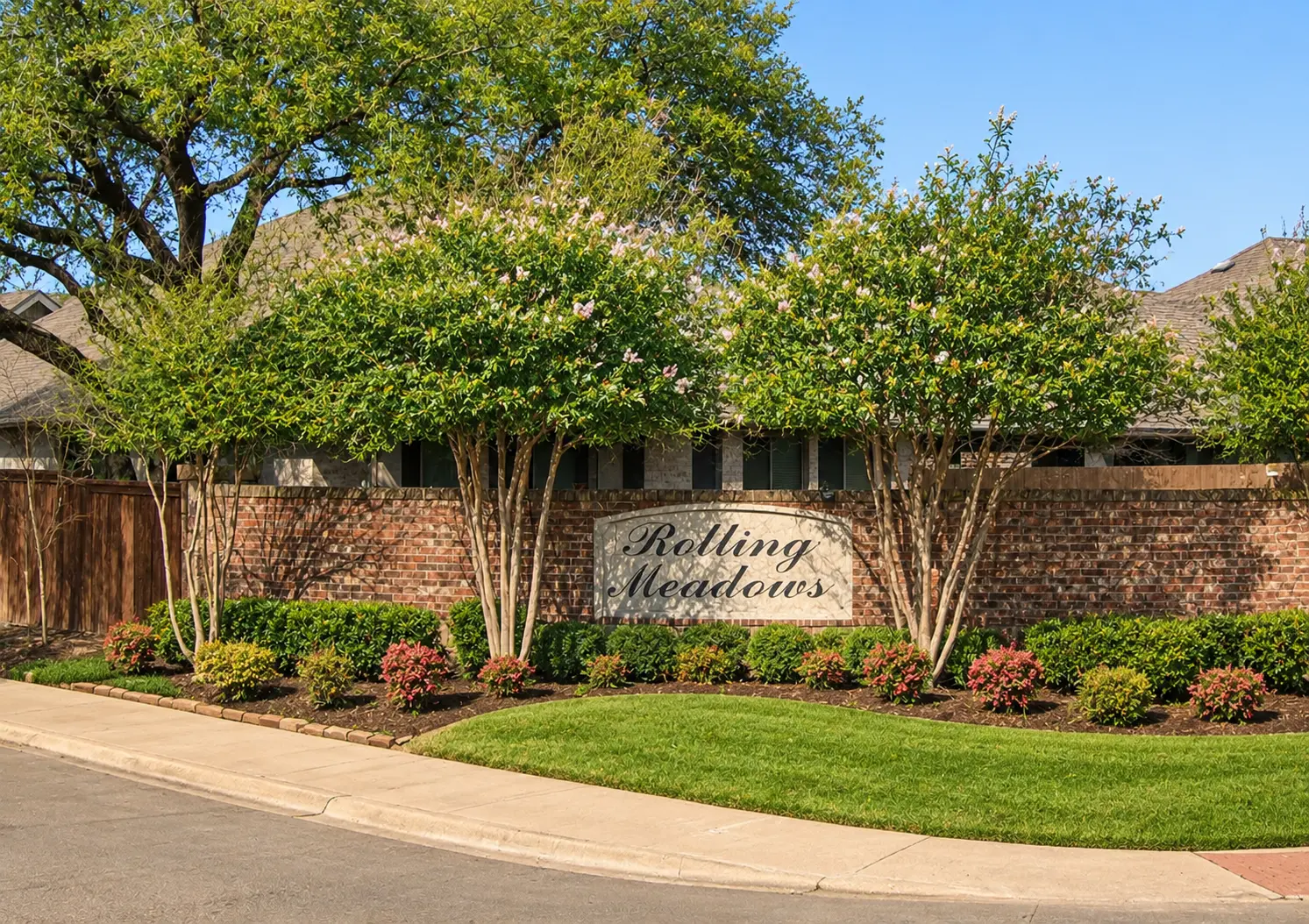 Rolling Meadows entrance monument sign framed by crape myrtles and manicured landscaping